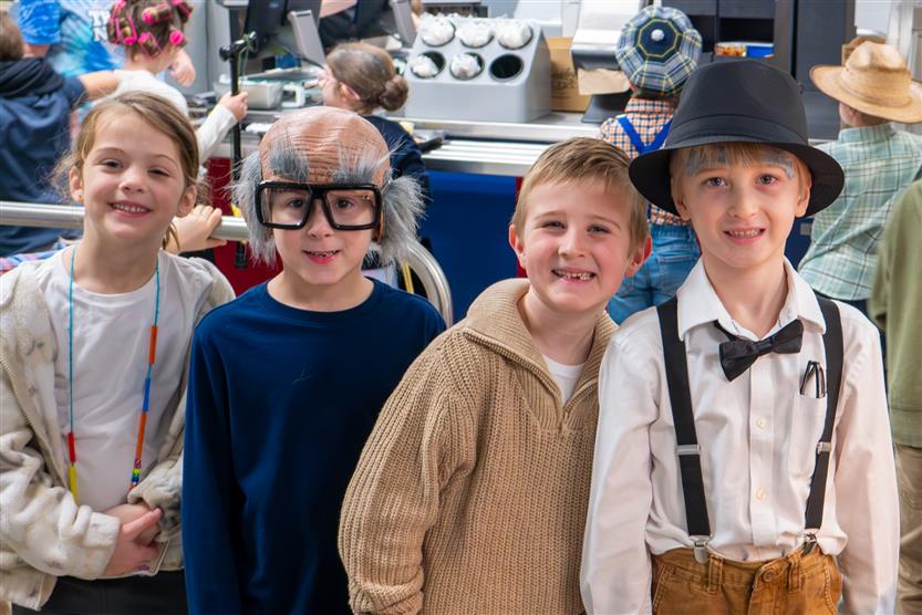 four students in 100 year old outfits
